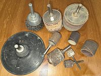Photo showing various sanding and grinding bits including wire brush, sanding drums with sleeves, and sanding disc