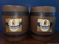 Two brown vintage mini kegs with wood barrel texture, black bands and Oktoberfest gold labels on front