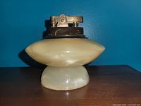 Side view of the vintage table lighter showing the pearlescent base and metal lighter mechanism on top