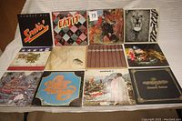 Overview of all 12 vinyl record album covers showing a variety of classic rock band artwork including Santana, Humble Pie, Jefferson Airplane, Chicago and Woodstock.