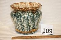 Front view of antique spongeware jardiniere showing scalloped upper edge and textured green and white sponge pattern with brown luster highlights on rim and base.