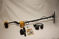 Assembled Garrett ACE 350 detector with shaft, control housing, coil and accessories laid on white backdrop