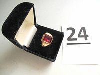 Ring displayed in black velvet presentation box alongside lot number card on white background