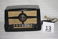 Front view showing the radio dial, tuning knobs, logo, and speaker grille.