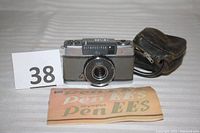 Front view of Olympus Pen EE-S camera with instruction manual and case