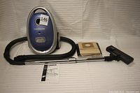 Full view of the Oreck vacuum with hose, telescopic wand, floor tool, instruction manual, and several vacuum bags on a white background.