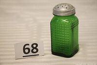 Front angled view of the green glass shaker with waffle pattern and aluminum top