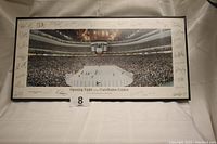 Front view of framed poster showing full panoramic ice rink with crowd and facsimile signatures around photo border