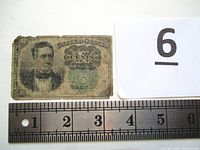 Two 10 cents shinplaster U.S. fractional currency notes placed next to a ruler to show size (approx 3.25 x 2 in).