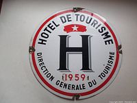 Full view of round enamel steel sign featuring Hotel de Tourisme logo, dated 1959.