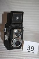 Front view of the vintage Graflex 22 camera showing twin lens reflex design, textured black body, silver lens rings, and 'GRAFLEX 22' nameplate.