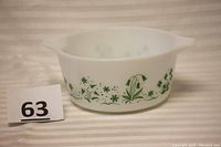 Side view of white Pyrex casserole featuring green floral design and a label with lot number 63.