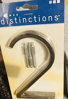 Clear image of packaged metal number 2 house number with included mounting screws, sealed on blue and white branded backing card.