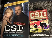 Two paperback CSI books by Max Allan Collins, titled Mortal Wounds and Sin City, shown side by side on a carpeted floor.
