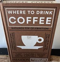 Front cover of the 'Where to Drink Coffee' hardcover book showing title, coffee cup illustration, and text mentioning over 500 cafes, coffee shops, and restaurants included.