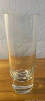 Full view of clear cylindrical glass vase on wooden surface