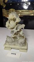 Front and side views of antique hand carved soapstone statue showing swans and flowers on a rectangular base