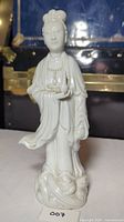Front view of white porcelain Guanyin figurine showing detailed facial features, flowing robes, and base.