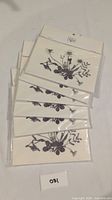 Six sealed packs of greeting cards with black and white floral artwork by Williamy, stacked overlapping on a flat surface.