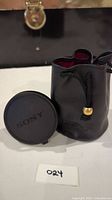 Sony wide conversion lens with front and rear caps next to black drawstring pouch