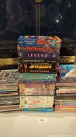 Stack of assorted media cases including video games, VHS, CDs, DVDs, Blu-Rays