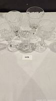 Photo showing all 5 vintage assorted crystal glasses arranged on a surface with various cut and etched designs visible.