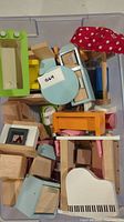 Top view of assorted wooden dollhouse furniture pieces including piano, table, bed, and other small furniture