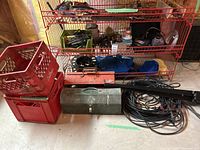 Wide view showing shelves with assorted tools, two red Santosi crates, metal toolboxes, and coiled cables on floor in front