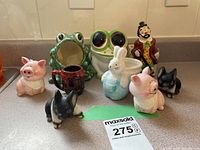 Front view of all figurines arranged on a countertop showing pig, frog, clown, bunny, and dog figurines.