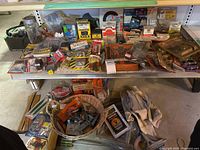 Shelf of assorted household hardware including nails, chains, gloves, tapes, and fasteners.