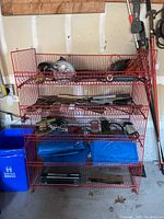 Full view of red wire shelves holding various tools and tarps, including SKIL circular saw and cords visible, several tarps folded on lower shelf