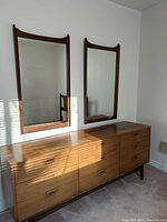 Front view of nine-drawer dresser with two mirrors mounted above on blank wall