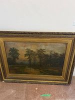 Full view of framed oil painting showing stream through woods and ornate gold frame