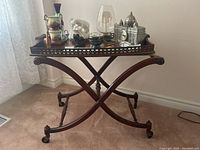 Front view of wood tea trolley showing ornate tray, X-shaped base with caster wheels