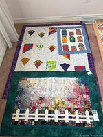 Photo of three quilts laid on the floor showing their designs and borders.