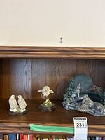 Wide shot of all three figurines on wooden shelf showing their size and arrangement.
