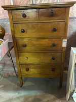 Front view of the wood dresser showing six drawers with wood knobs, two small on top and four larger below, mounted on castors.