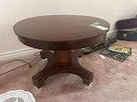 Front view of the round wood pedestal table showing the tabletop and base structure