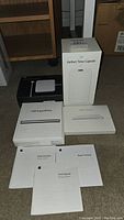 Apple AirPort Time Capsule in original box, USB SuperDrive box, Magic Trackpad box, MagSafe Power Adapter and setup guides arranged on floor.