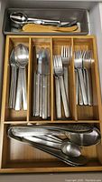 Drawer with stainless steel flatware including spoons, knives, and forks, plus serving spoons