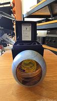 Paperweight in front of open Glass Eye Studio box with MaxSold label