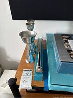 Photo showing all three items: kiddush cup, candle sticks, and bread cutter alongside their original boxes on a wooden surface.