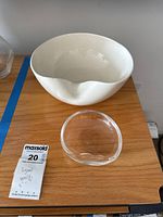 Photo of clear glass and white ceramic bowls on wooden surface showing size and form.