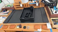 Overall view of black leather desk mat with trays, pen cup, and tan leather pieces