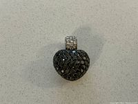 Front view of heart-shaped pendant showing pavé black diamonds and diamond-set bail
