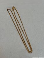 Full view of gold chain laid flat showing entire length and clasp
