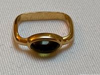 Front view of square gold band with bezel-set green oval stone on white background