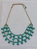 Full view of necklace showing three-tier turquoise bead fringe and gold curb chain