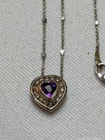 Close-up of heart-shaped pendant front showing purple amethyst center and diamond halo