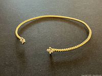 Open view of gold rope cuff bracelet laid flat on black background